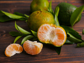 Jeruk keprok, fresh tangerines with green leaves on wooden table, fresh orange fruit, ripe...