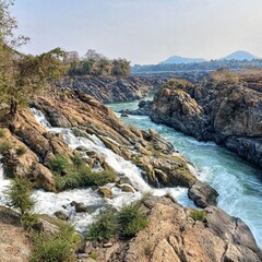 Fototapeta premium Fast flowing river rapids through rocky canyon with green water and natural landscape