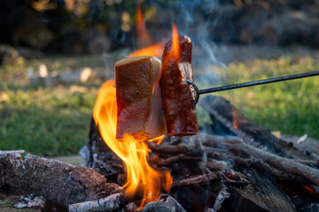 Traditional Hungarian campfire cooking with bacon and sausage on a skewer