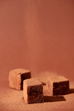 Vertical image of dessert, sweet cubes with chocolate flour isolated on brown background