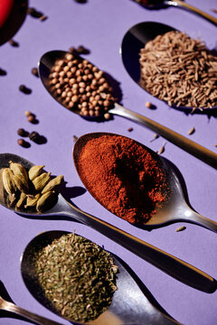 Vertical image of spoons lying in a row with paprika spices