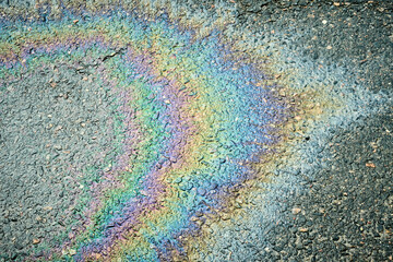 Fototapeta premium Iridescent gasoline spill creating a rainbow effect on a wet asphalt road