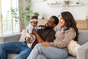 African family happy play at home, loving father holding and playing with baby while mother watches with joy, happy parenting moment full of love, affection, care and connection in cozy family at home