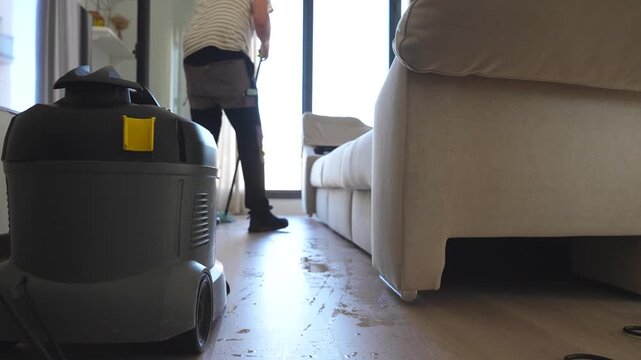 Man scrubbing the floor of his client's house after cleaning the sofa with ionized water to eliminate germs and bacteria without damaging the fabric