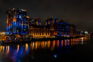 Contemporary residential buildings brightly lit with blue and orange lights at night, reflecting on...