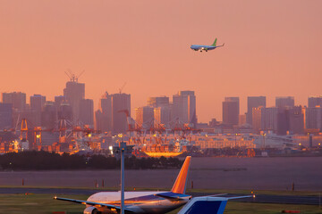 夕焼けの羽田空港のデッキ。
離発着する旅客機と夕暮れの東京の町並みが見える。
東京都大田区東京国際空港（羽田空港）-2025/6/26
