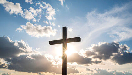 Silhouette of a Wooden Cross Against a Cloudy Sky with Sunlight and Rays Shining Through the Clouds