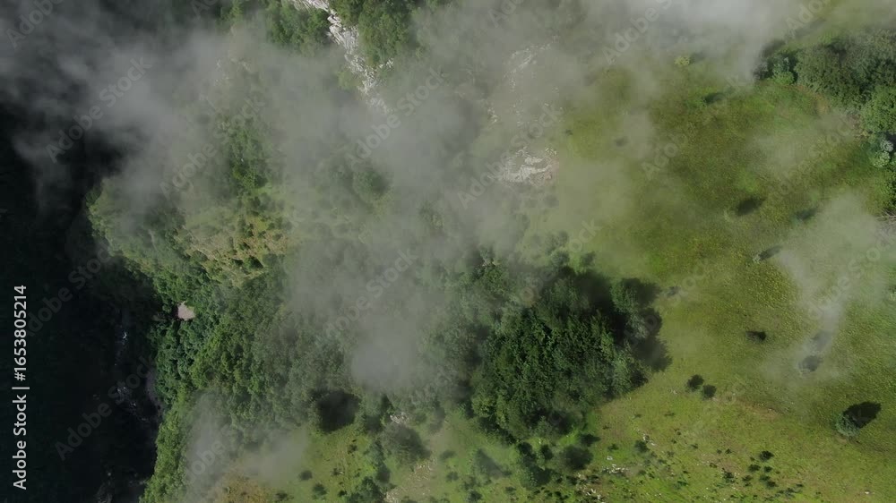 Aufkleber aerial view of terrain with trees and water partially covered in fog the ground is green rocks and s