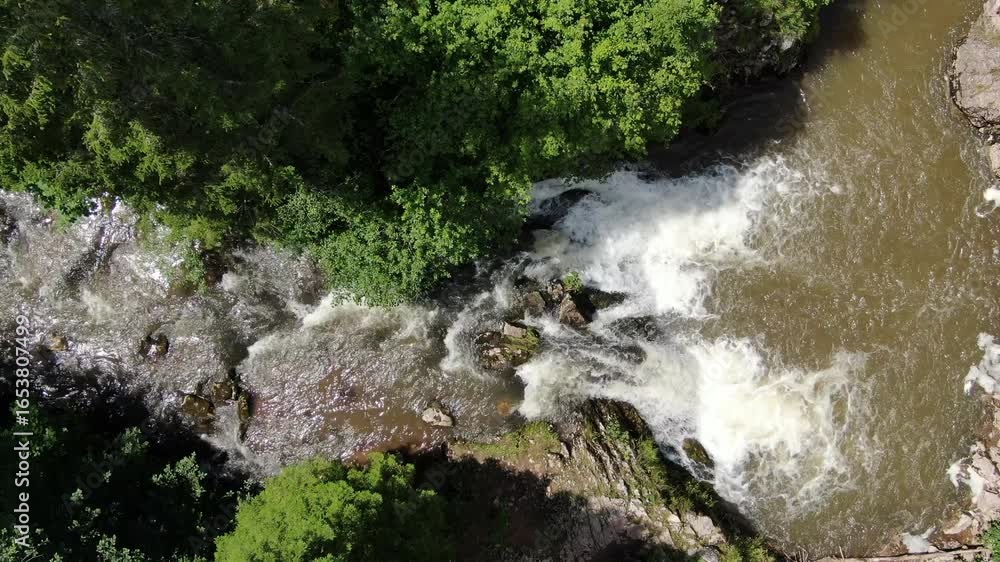 Aufkleber water flows through rocks and trees the river runs fast over a small waterfall surrounded by forest 