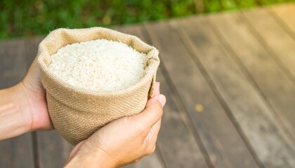 Hands holding a burlap sack filled with fluffy, uncooked white rice, a staple food for sustenance, offering a glimpse of culinary possibilities and agricultural bounty, embodying healthy eating
