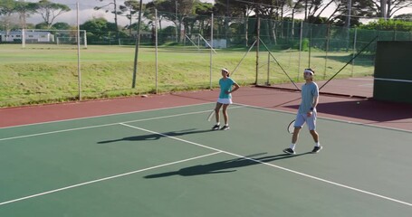 Incoming shot prompting diverse tennis partners on hardcourt shuffling volleying bumping rackets - Powered by Adobe