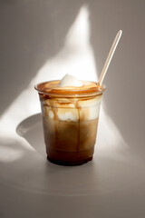 Einspänner coffee (Vienna coffee). Coffee topped with cream. Served in a clear disposable cup with a wooden stick.