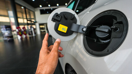 man’s hand inspecting a car by opening the fuel cap during a quality check at an automotive service center. Professional maintenance and repair process ensuring vehicle safety and performance.