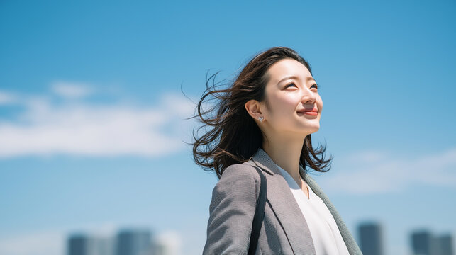 青空の下で都会を背景に立つ爽やかなビジネスウーマン「生成AI」