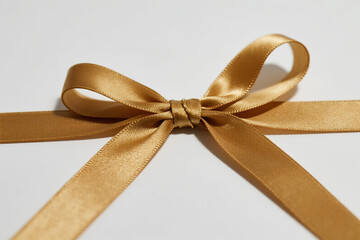 Elegant golden bow with symmetrical satin ribbons, smooth glossy texture and natural draping ends on pure white background, minimalist luxury concept