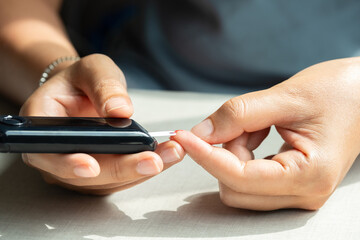 Woman's hands checking diabetes and hyperglycemia with digital blood sugar meter. Healthcare and...