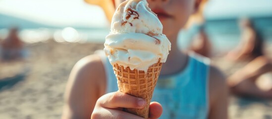 Child holding ice cream cone on beach