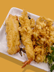 Golden and crispy shrimp tempura served on a white plate on beige background. Japanese dish. National Tempura Day to celebrate on January 7th