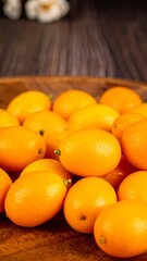 A wooden bowl overflows with vibrant, ripe kumquats