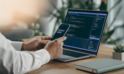 Close-up view of a person working with a laptop and a smartphone, showcasing the concept of technology and communication in the digital age.