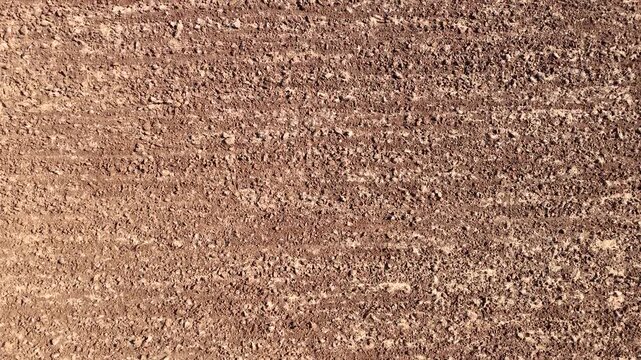 An excellent 4K top-down aerial video of a freshly plowed agricultural field with rich dark soil tilled into a rough clumpy texture ready for planting a new crop season