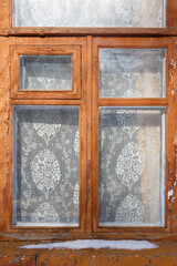 Vintage wooden window with lace curtain in brick wall