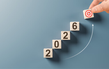 Hand putting wooden block with target icon to complete 2026 stair, representing business growth,...