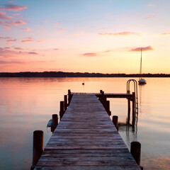 sunset on the wooden pier over the idyllic lake