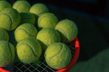 Tennis balls casually placed on a tennis racket with sunny day and sunshine
