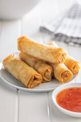 Fried spring rolls on plate on white table.