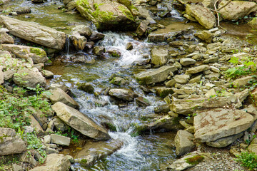 A stream of water flows between large rocks