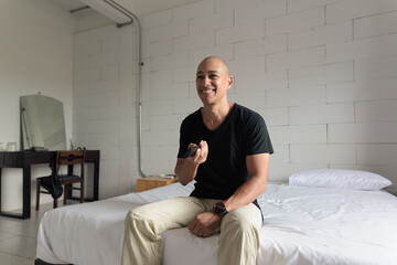 Happy man sitting and watching television at home while sitting on bed