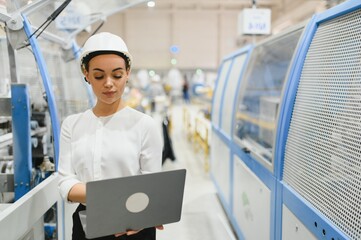Female industrial engineer working on laptop in a modern factory