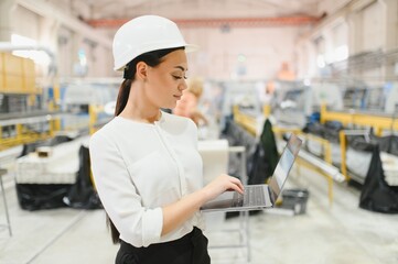 Female industrial engineer working on laptop in a factory