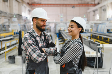 Smiling industrial workers posing with crossed arms in factory