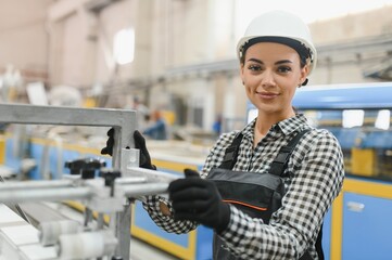 Female factory worker operating machinery in window manufacturing plant