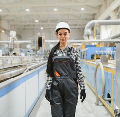 Female factory worker wearing hardhat and overalls in pvc manufacturing plant