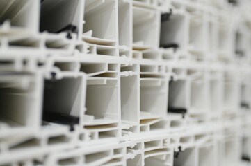 Stacked white pvc window frames in factory, manufacturing process of plastic windows and doors