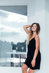 Obraz premium Slim blonde woman in black summer dress smiling