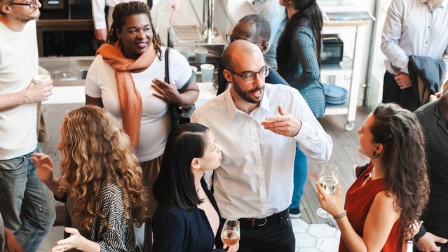 Diverse group of people at social event, mingling and chatting. Diverse crowd enjoy drinks and conversation in lively social gathering party. Social event with diverse group of people mingling