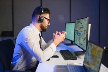 Center of dispatching maintenance. Portrait of man working via headset microphone while sitting on navigation controller board