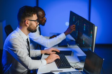 Conception of teamwork. Team of stockbrokers works in modern office with many display screens