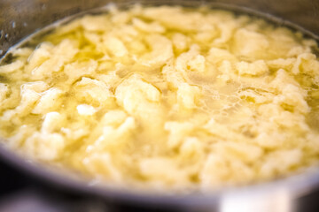 Cooking broth with dumplings in a pot.

