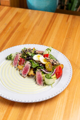 Salad with fried tuna pieces. On a wooden table.