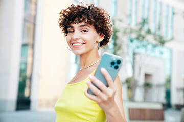 Young beautiful smiling hipster woman in trendy summer clothes. Carefree woman with curls...
