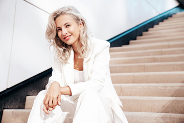 Young beautiful blond woman wearing nice trendy white suit jacket. Smiling model posing in the...