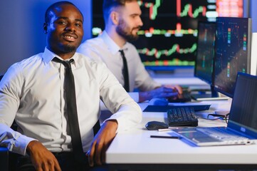 African american male stock trader or broker working at stock exchange office using computer