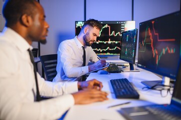 Conception of teamwork. Team of stockbrokers works in modern office with many display screens