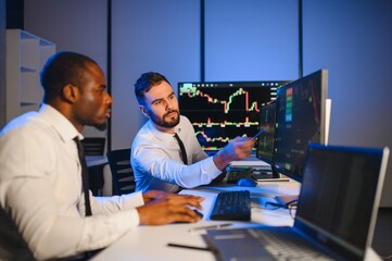 Conception of teamwork. Team of stockbrokers works in modern office with many display screens
