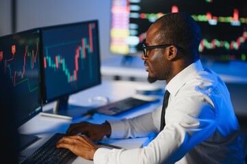 Obraz na płótnie Canvas African american male stock trader or broker working at stock exchange office using computer